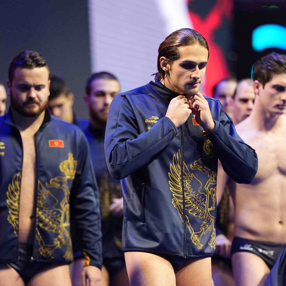 Man adjusting his jacket with other men in the background at a sports event.